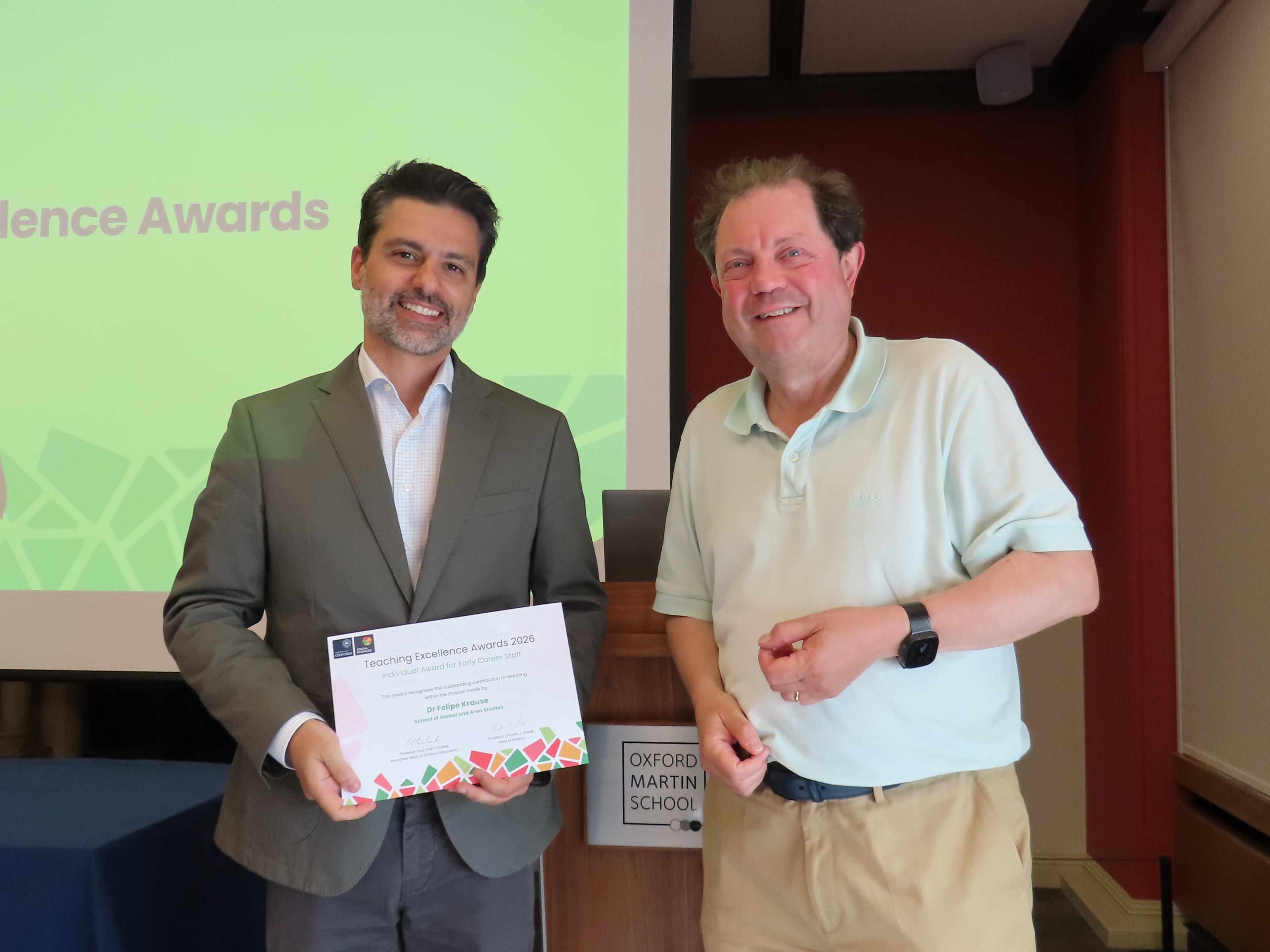 Dr Felipe Krause, wearing a grey blazer and holding a certificate, stands next to Professor Paul Irwin Crookes