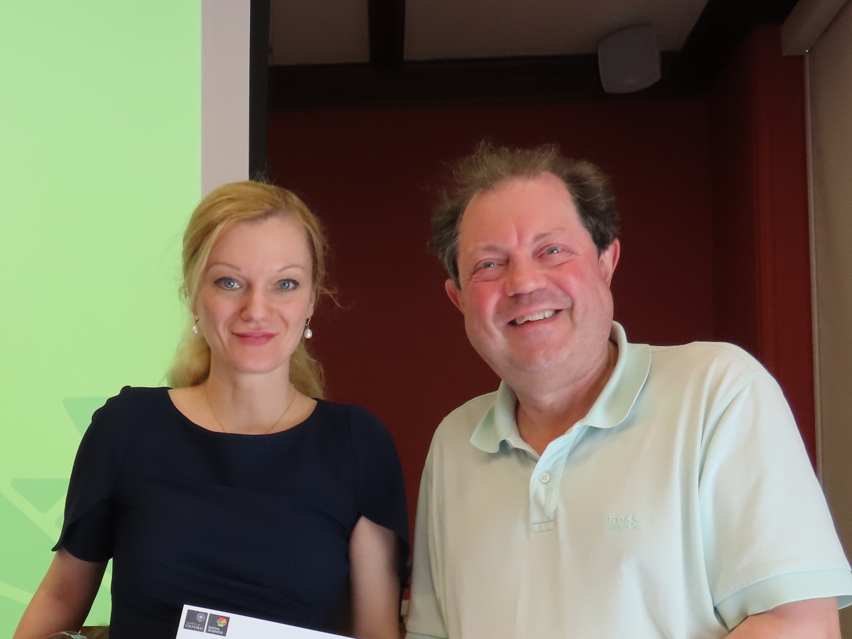Professor Janina Dill, wearing a dark dress and with long blonde hair in a ponytail, standing next to Professor Paul Irwin Crookes