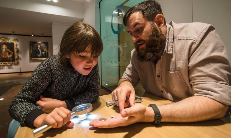 Photo of adult and child looking at historical coins in the Ashmolean Museum