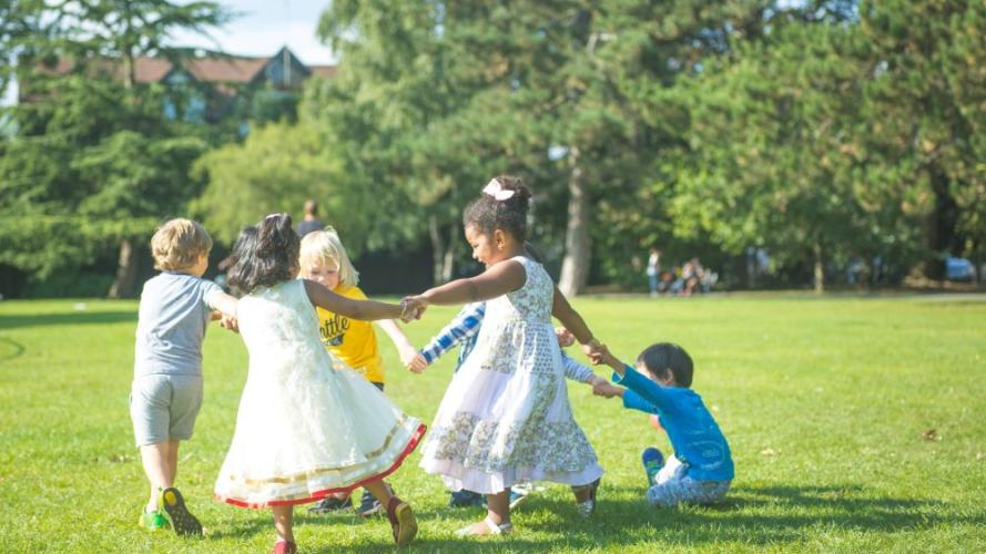children playing in a green space with trees