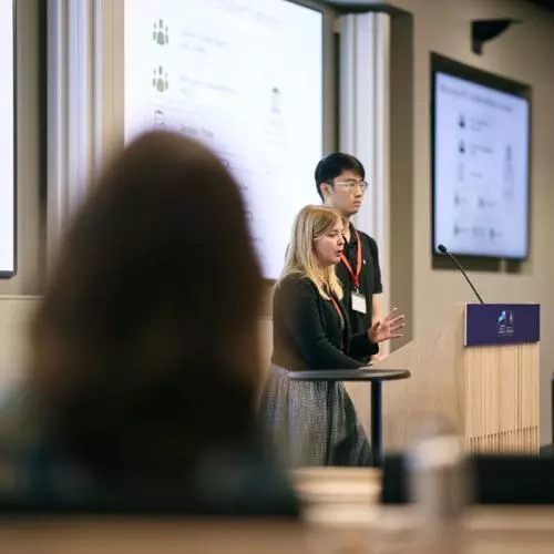 Two young people address the audience from a lectern