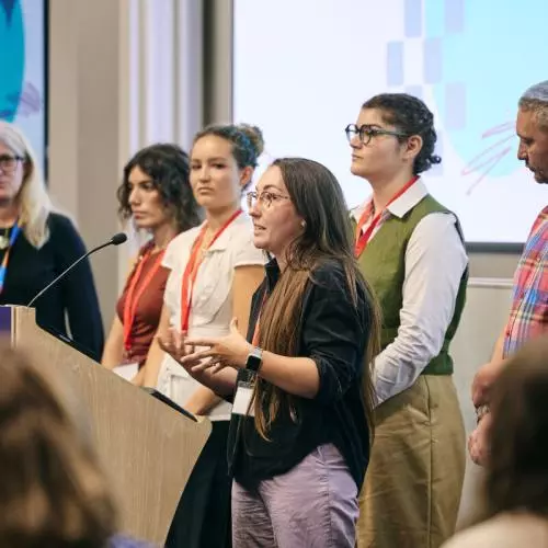 A group of young people address the audience from a lectern