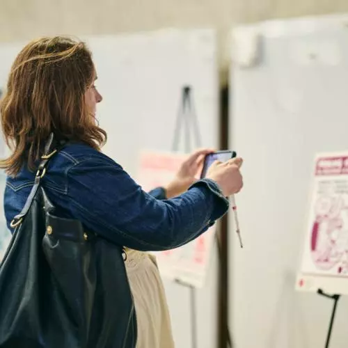A woman takes a photo of a poster with her phone