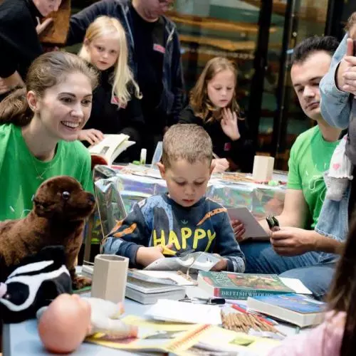 children and researchers around a table with craft items and paper