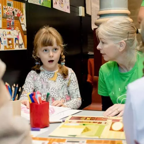Young girl looking surprised and drawing sat at a table with a resercher
