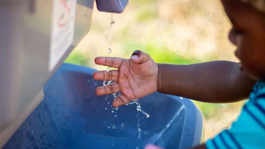 A young child washes their hands