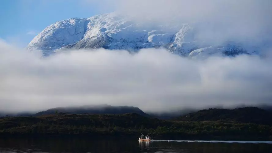 people in a boat on a river in Chile with mountains in the background