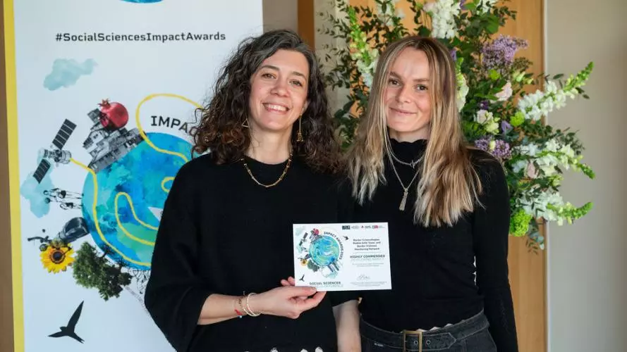 Dr Andriani Fili and colleague smile while holding their 2025 Social Sciences Impact Award 
