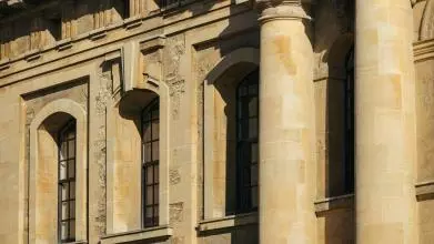 A close-up of columns and windows in an old building built from yellow stone