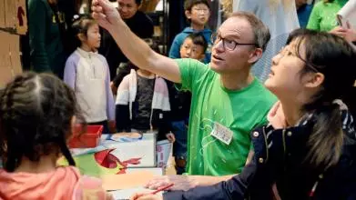 Researcher showing lady an object in museum cabinet