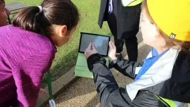 Researcher explains data on an ipad screen outside on a sunny day