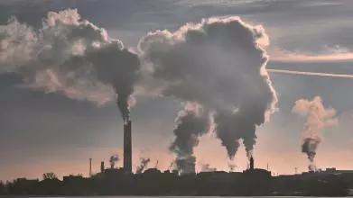 Silhouette of big clouds of emissions billowing into the sky from an industrial plant