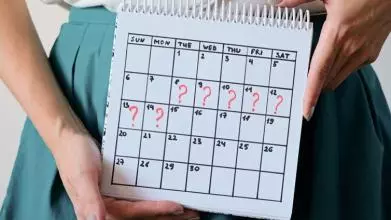 The hands of a woman holding a calendar, which shows 7 consecutive days marked with a question makr
