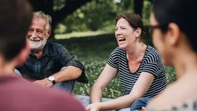 A woman smiles and laughs in conversation with a group of people