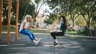 Friends sit on park swings