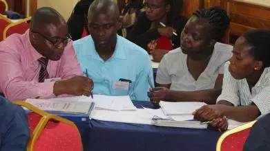 Four school leaders in discussion, seated around a table