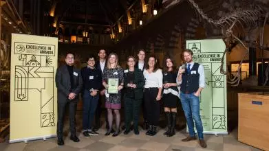 Professor Melinda Mills, Dr Jennifer Beam Dowd, and colleagues from the LCDS team smile as they hold their Impact Awards winners certificate, in front of the O2RB Excellence in Impact Awards event branding