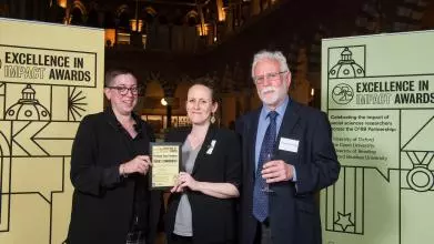 Prof Rosa Freedman holds the Highly Commended award with Sarah Blakemore and Alex Dressler, flanked by event branding at the awards reception