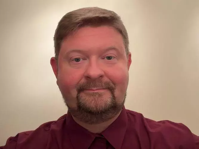 Andy has fair hair and is smiling into the camera