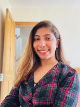 South Asian woman smiling with long fair hair and checked jacket