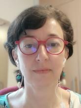 White woman with red glasses and short brown hair
