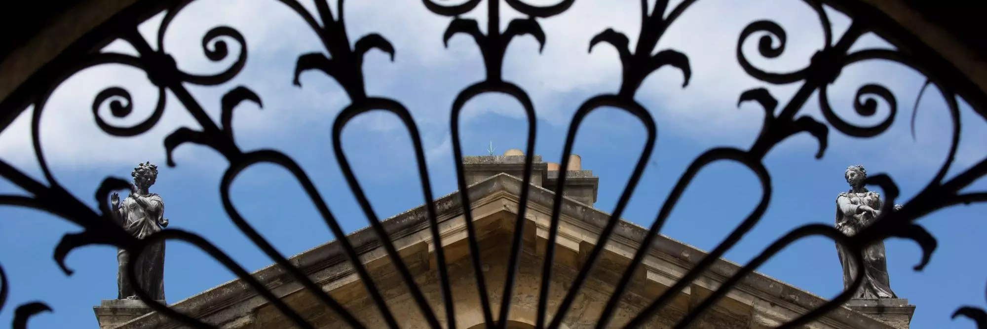 The roof of the Clarendon Building, seen through an arch of ornate railings