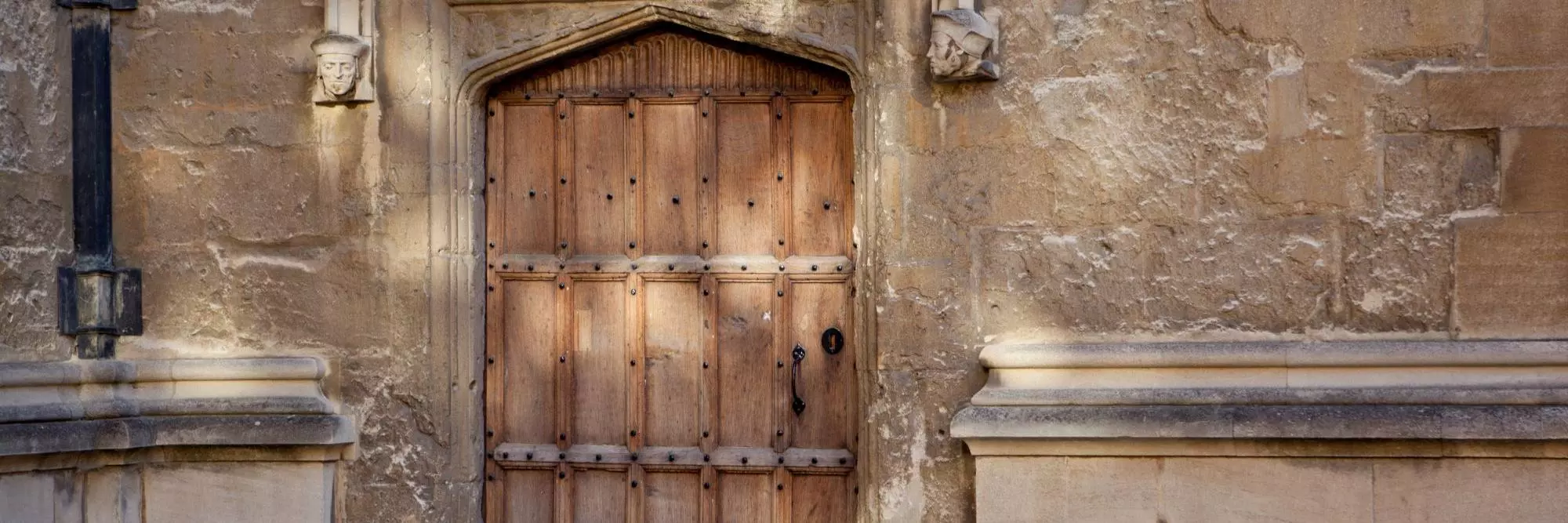 A wooden door in an old stone building, with painted words in Latin script over the frame