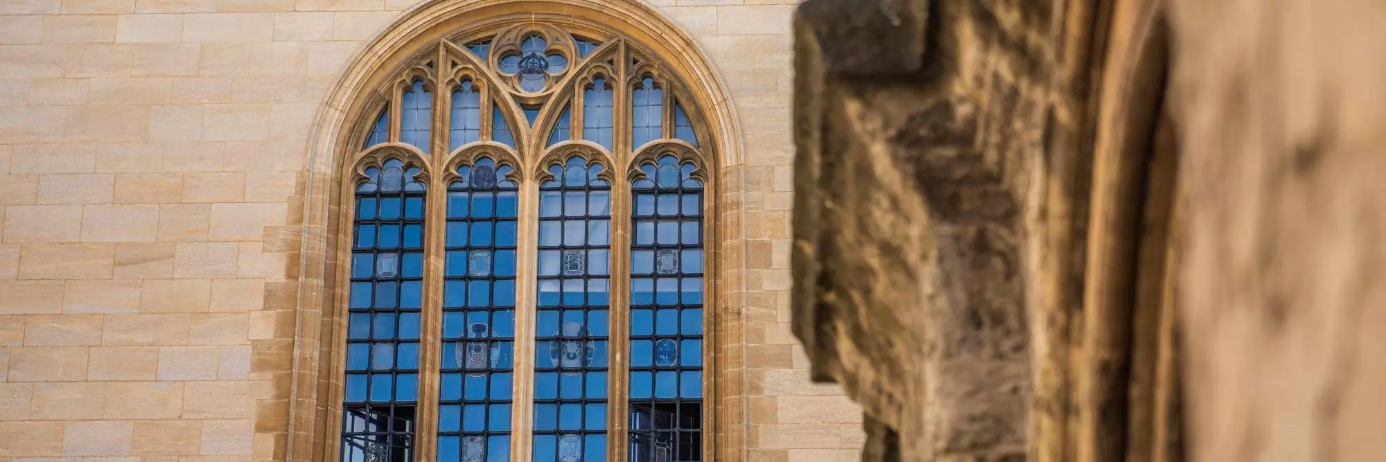 An ornate stone window on the top floor of a library building