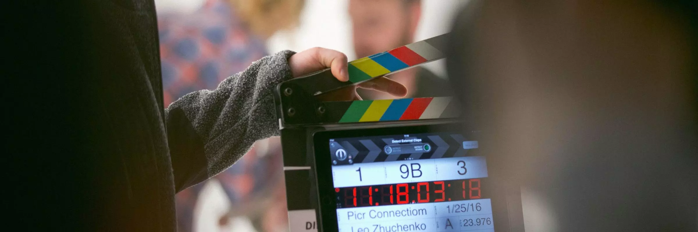 A film crew holds a clapperboard in front of actors on set