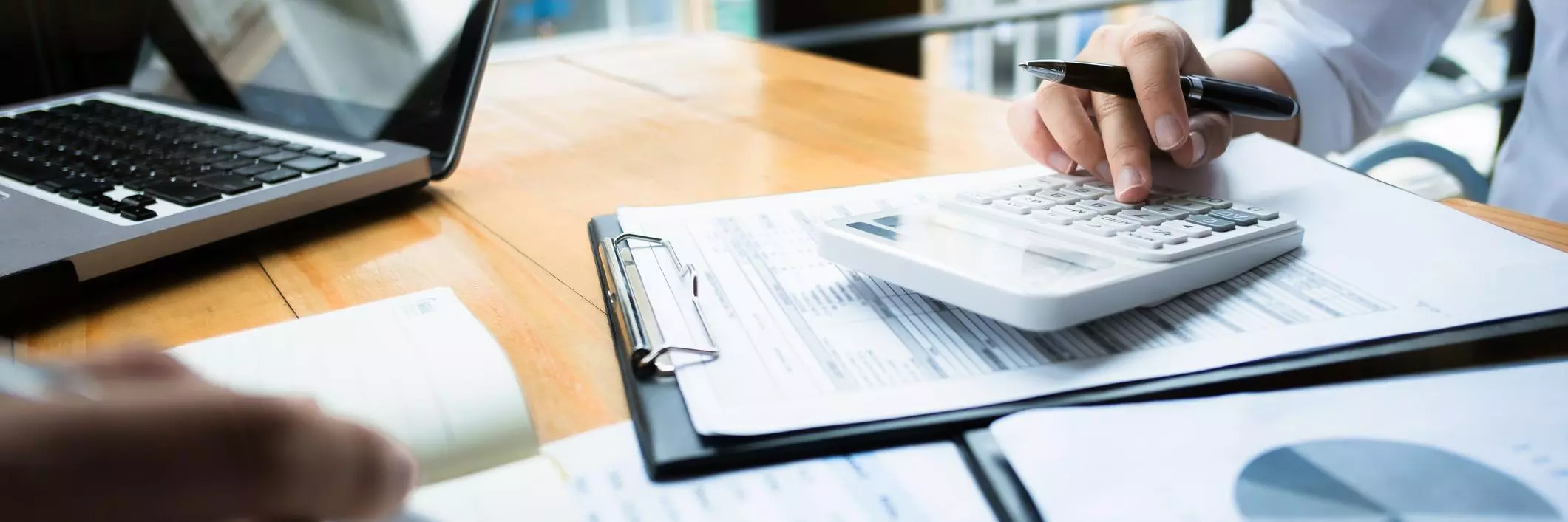 Two businessmen work over a calculator and some papers showing financial data