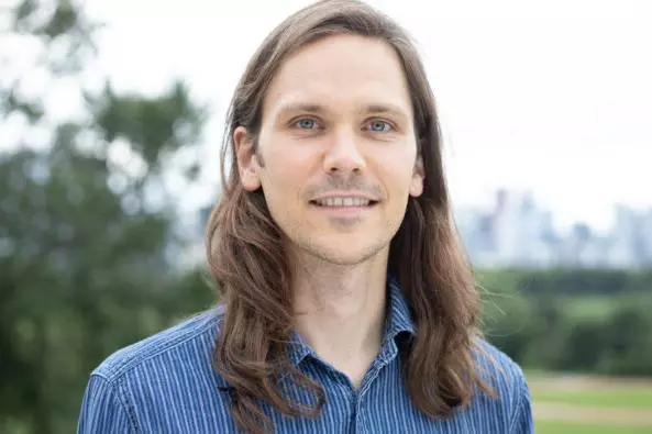 Dr Edmonds has long brown hair and is wearing a blue shirt