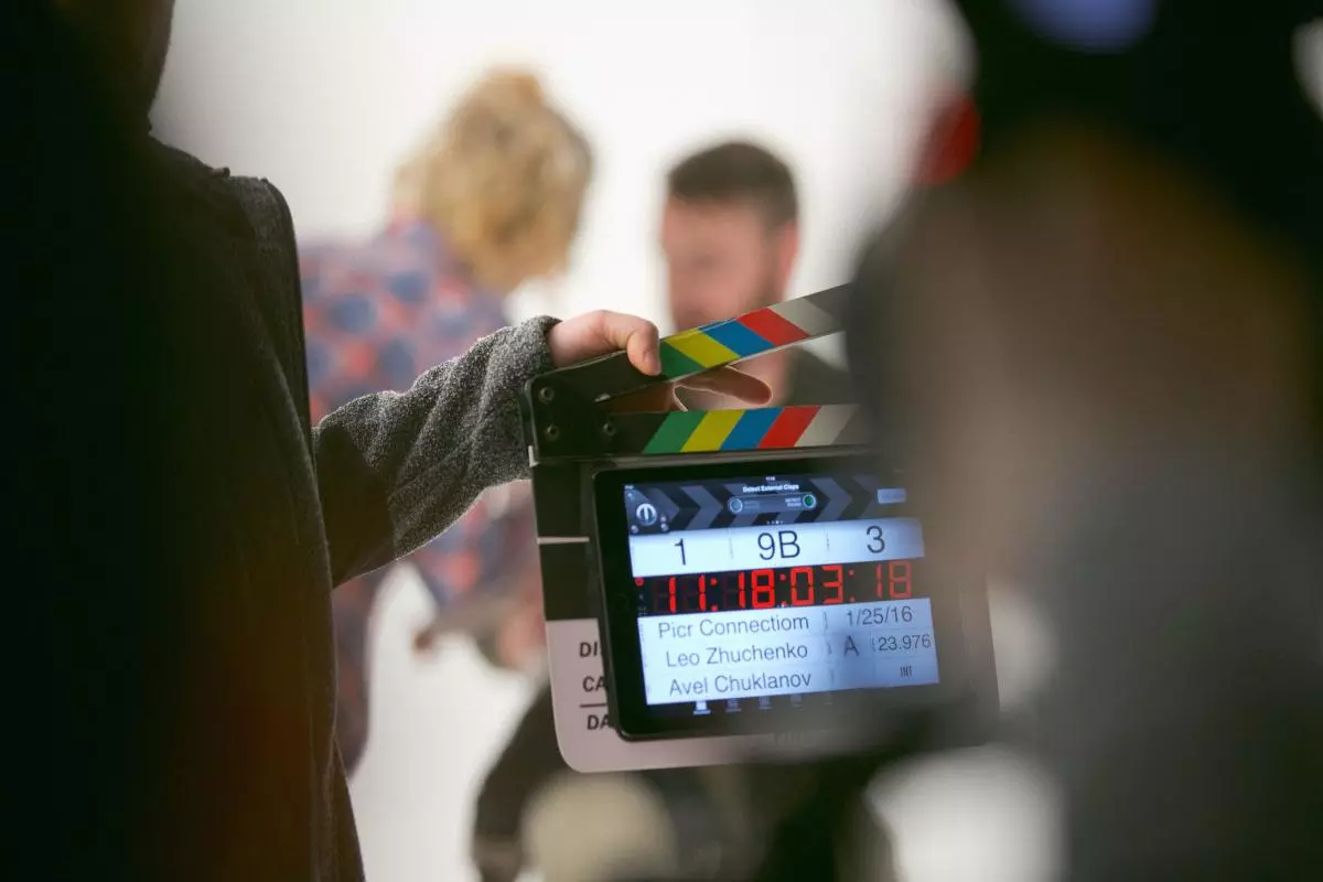 A film crew holds a clapperboard in front of actors on set
