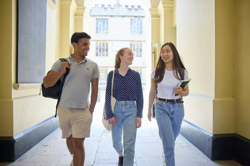 Three University students walking through an archway of a building chatting